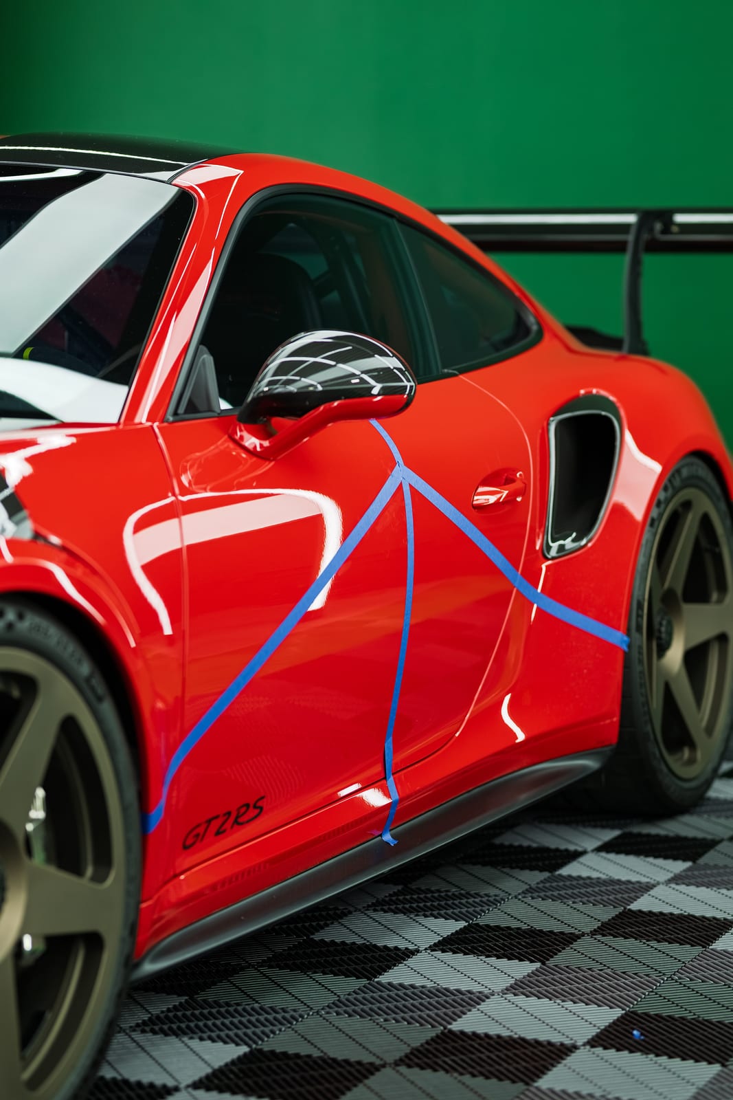 Side profile of a wrapped red Porsche GT2 RS on bronze wheels at WRPD
